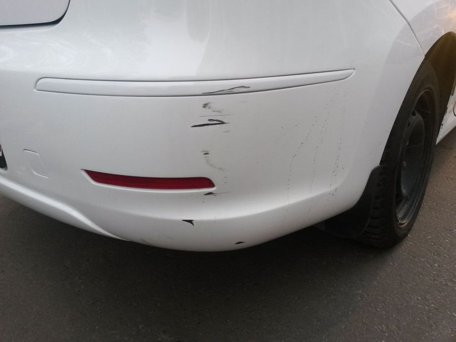 Close up of a scratch on a white car bumper